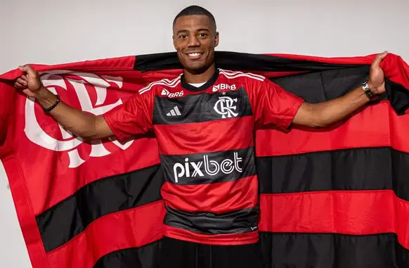 De La Cruz com a bandeira do Flamengo em sua chegada (Foto: Paula Reis / CRF)